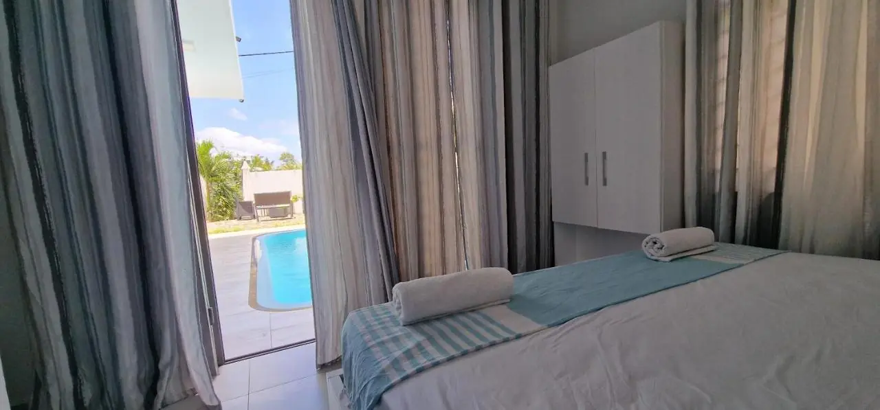 Air-conditioned modern bedroom with glass doors opening directly to the private pool in Grand Baie, Mauritius